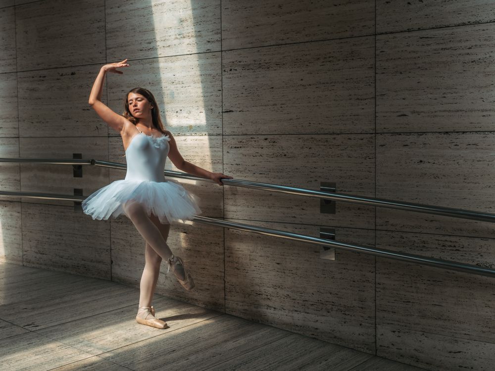 Ballerina doing pas at rail in classroom