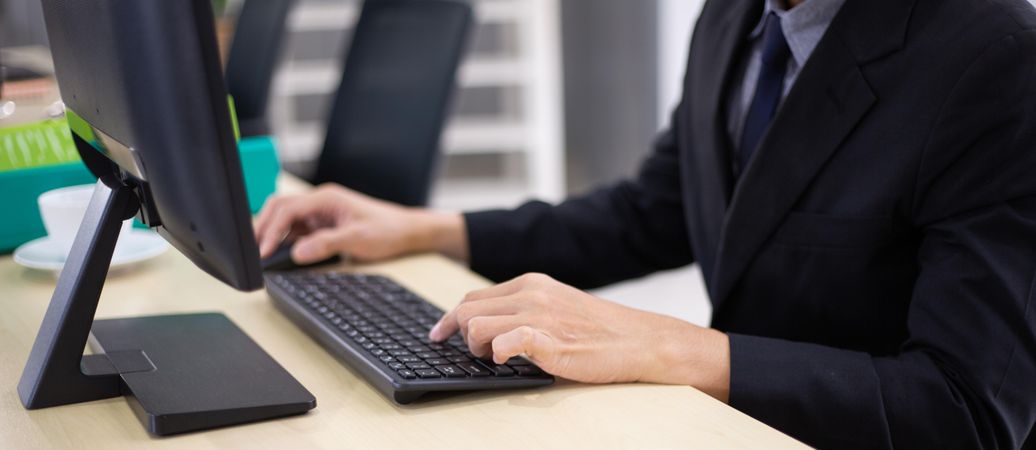 Male employee typing on computer keyboard at desk