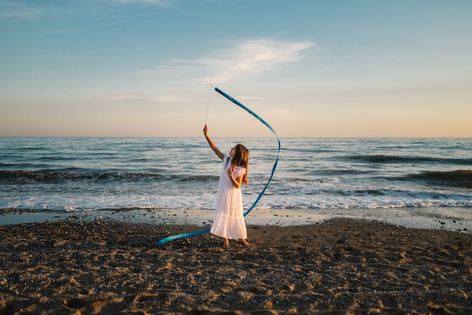 Adorable girl playing with ribbon on seaside