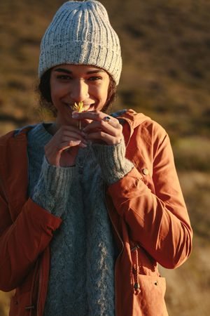 Portrait of young woman in winter wear smelling a flower
