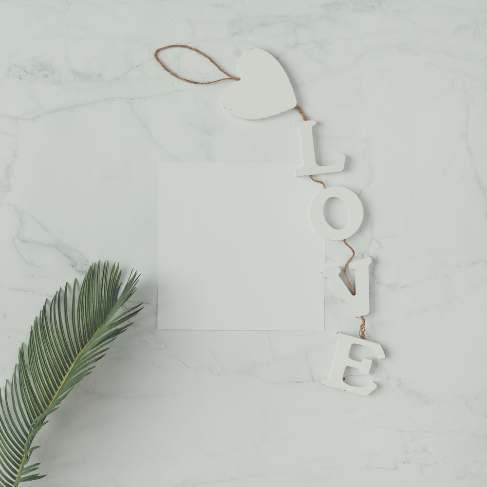 Palm leaf on marble background with the word “Love”