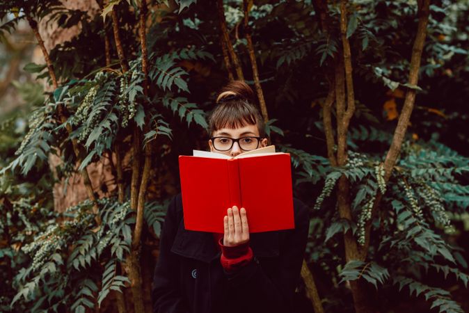 Young woman reading book on bench in park