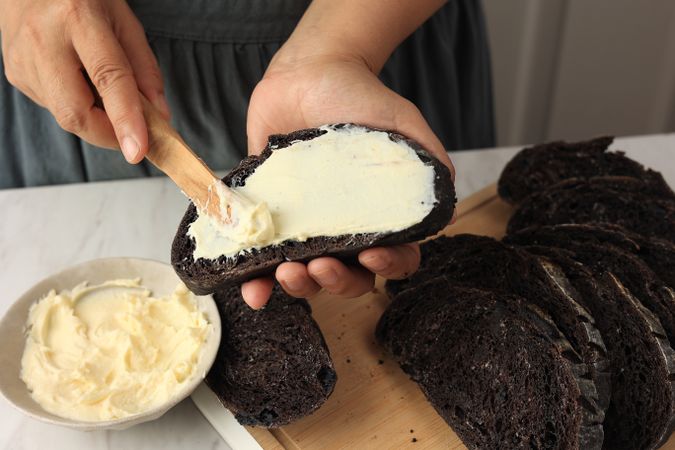 Spreads Cream Cheese with a Wooden Cutlery Knife to the Chocolate Sourdough Bread.