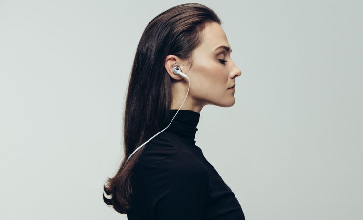 Woman wearing earphones against grey background