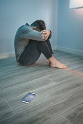 Man with problems sitting on the floor with mobile on the floor