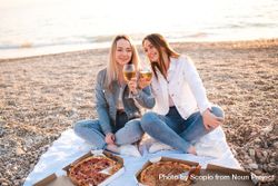 Two women enjoying pizzas and wine at the beach 56E7N0