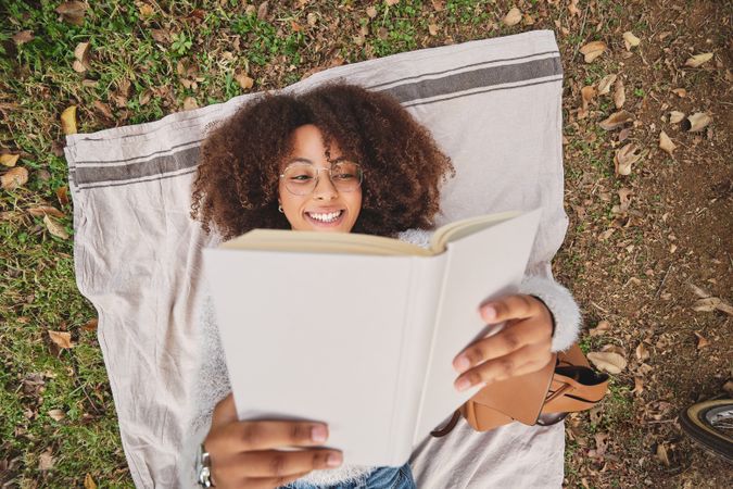 Positive Black Latina female reading book in park