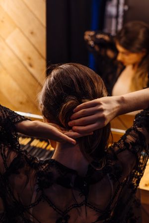 Female actress making hairstyle by illuminated mirror