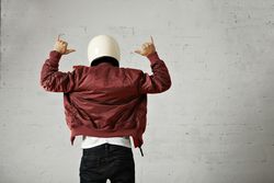 Rearshot of man with hands in the air wearing dark red leather jacket and helmet