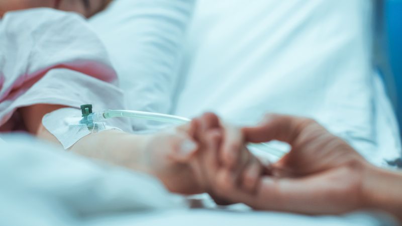 Recovering Little Girl Lying in the Hospital Bed Sleeping, Mother Holds Her Hand Comforting.