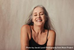 Older woman smiling in bikini top in a studio 0KpGZ5