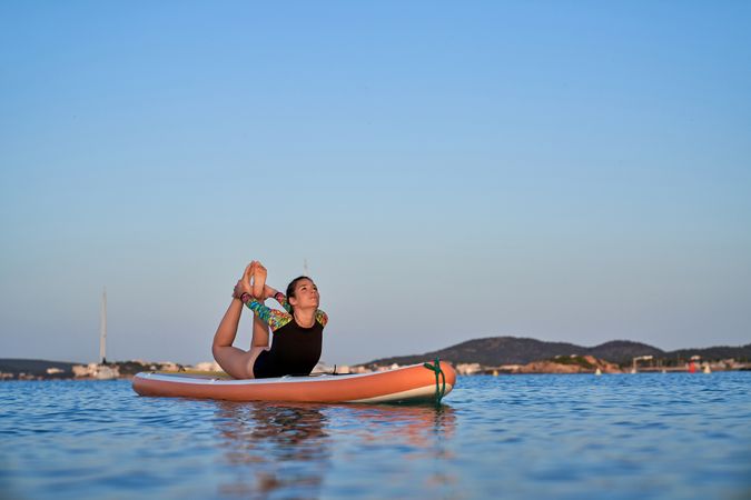 Woman doing Bow yoga pose on paddleboard