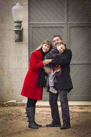 Warmly Dressed Family Loving Son in Front of Rustic Building
