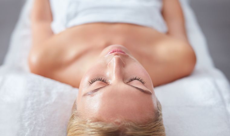 Blonde woman lying back and relaxing with eyes closed after beauty treatment