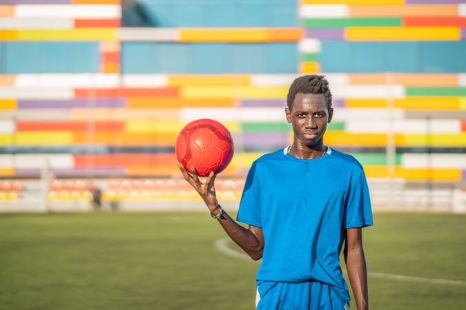 Black teenager with football ball against sky