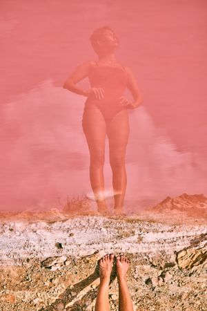 Fit woman in swimsuit posturing on pink lake shore