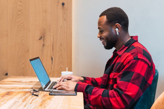 Smiling Black man working on laptop in cafe