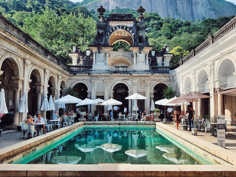 People sitting on tables surrounding swimming pool in a restaurant