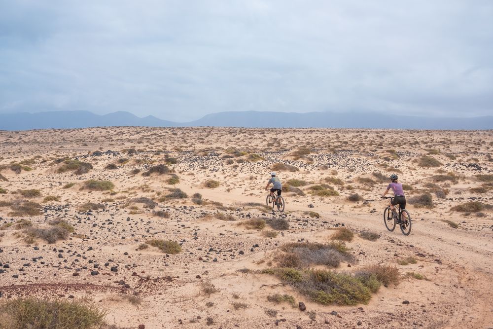 Side of man and woman biking on rugged terrain
