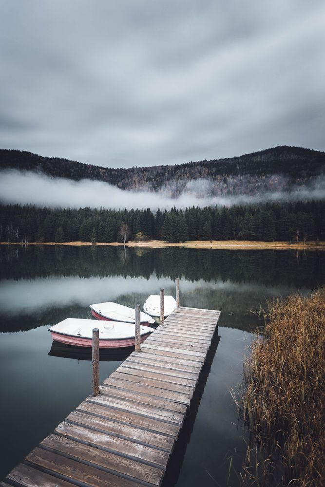 Three dinghies near brown wooden dock on lake