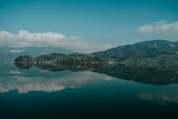 Large hilly coast with forest surrounded by clear lake