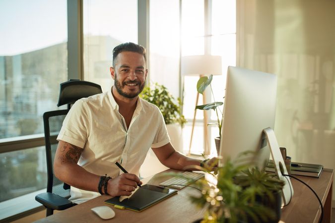 Handsome male designer working at his desk and smiling