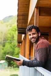 Thoughtful man reading book on terrace of house