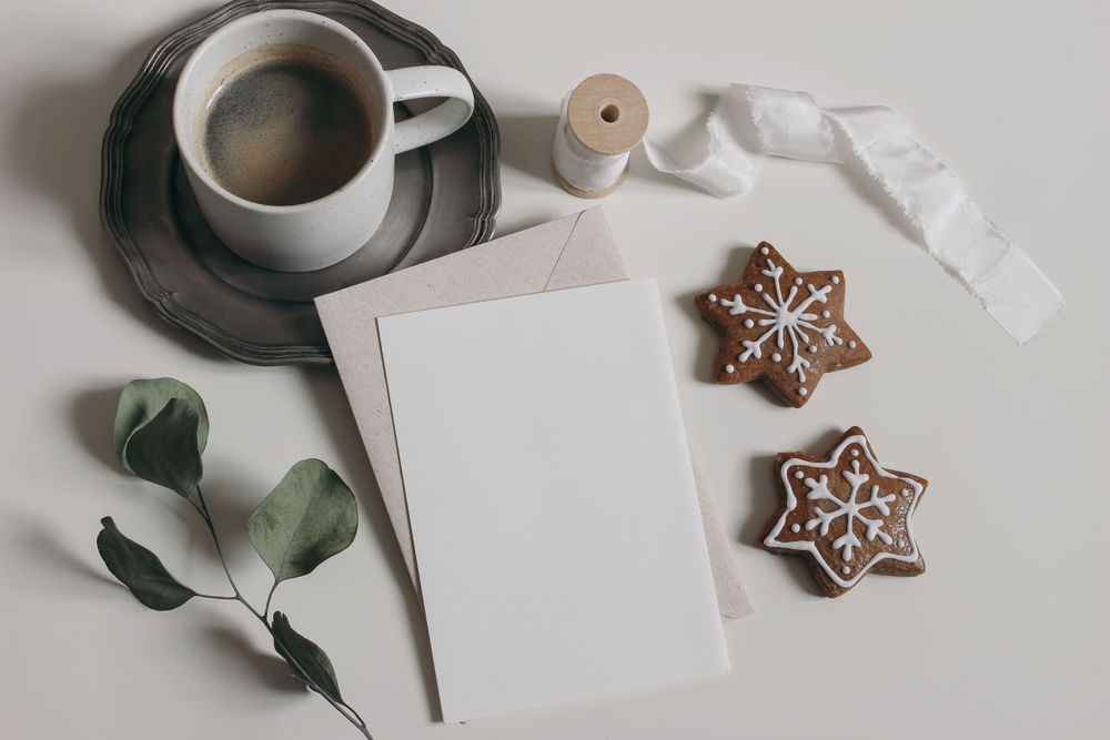 Christmas still life with blank card next to gingerbread cookies and warm drink