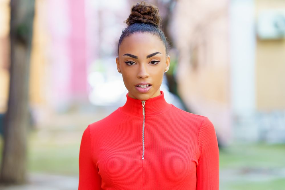 Female in red zipped up shirt standing outside