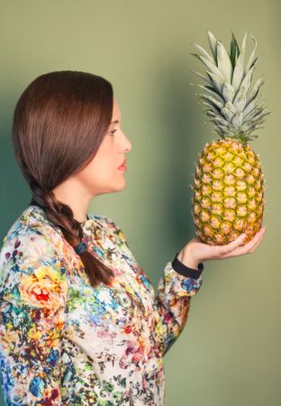Woman looking a pineapple in her hand