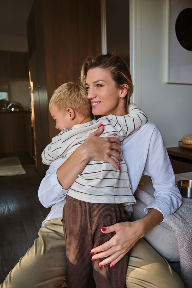 Positive woman and boy hugging each other in apartment