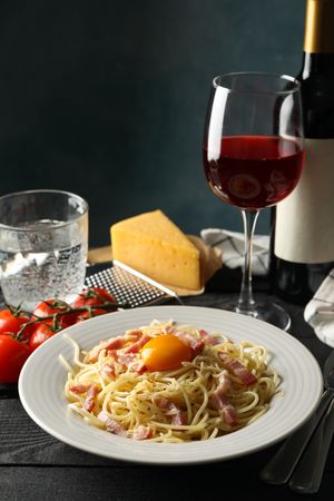 Composition with plate of tasty pasta and wine on wooden background