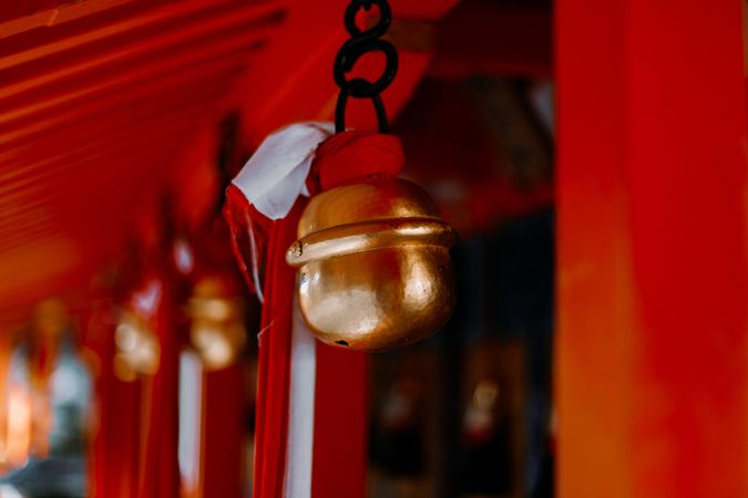 Selective focus photography of a bell tied to red fabric