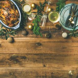 Roast chicken, plate, festive decorations, crystal flutes on wooden table, square crop