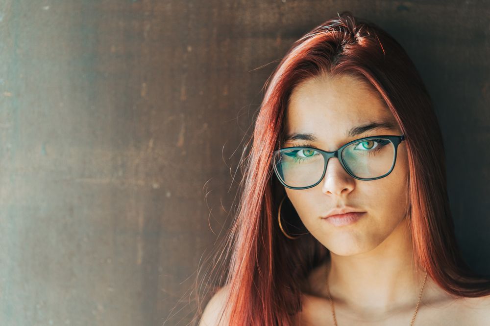 Woman in glasses leaning on wall