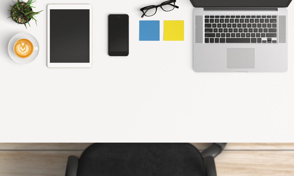 Modern workplace with laptop, coffee cup and smartphone or tablet copy space on table background. Top view. Flat lay style.