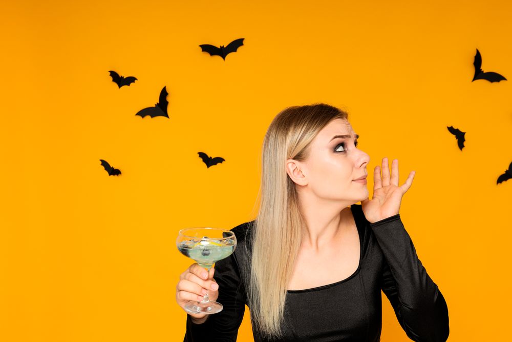 A woman at a party in the style of Halloween with a cocktail in her hands