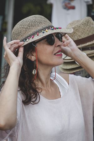 Woman choosing summer hat on street market