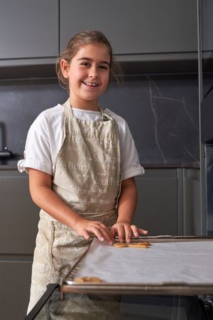 Glad kid putting piece of dough on baking sheet
