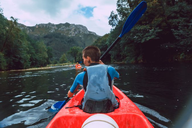 Female kayaking with paddle in raised hands