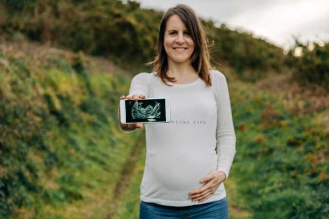 Pregnant woman showing ultrasound on the mobile