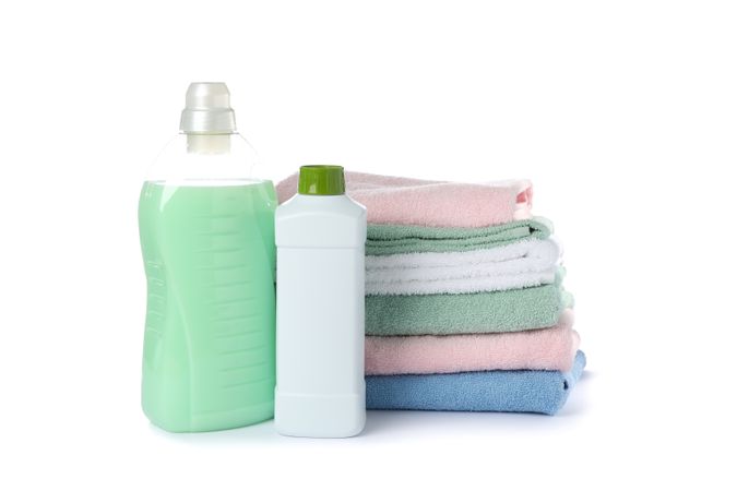 Laundry detergent and folded towels isolated on blank background