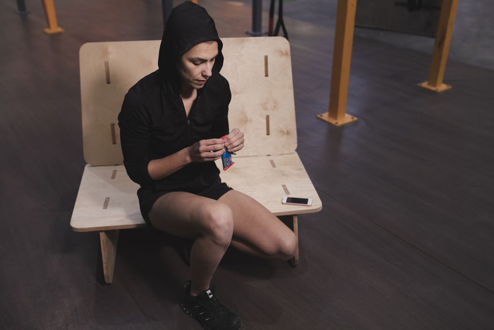 Smiling woman with energy bar in gym