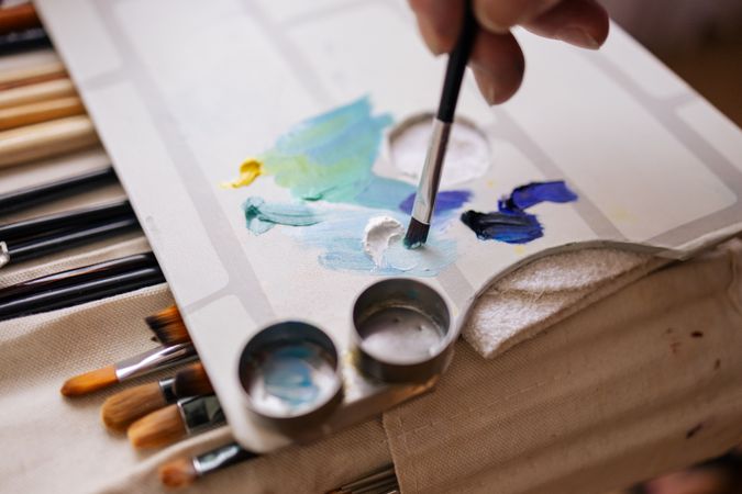 Close-up of a hand with a brush on a paint palette
