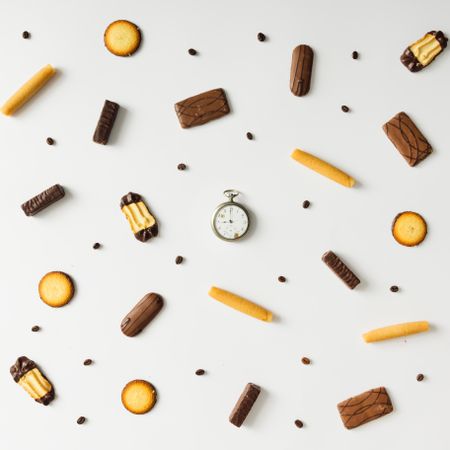 Hand clock with cookies and coffee bean pattern on light background