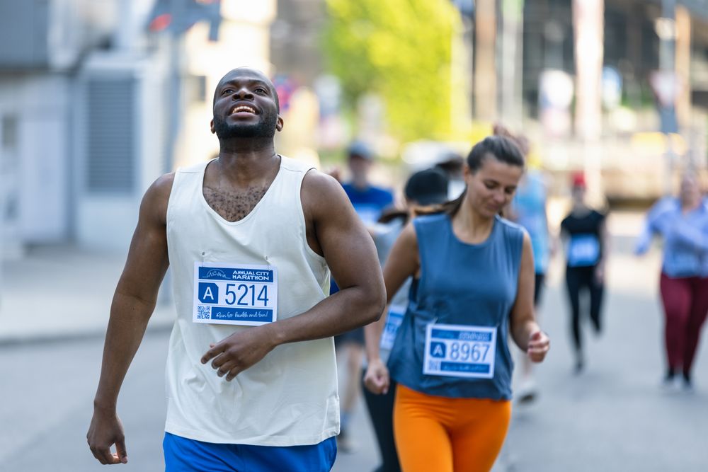 Portrait of Smiling Young Black Man Running in a City Marathon, Waving at the Supportive Audience