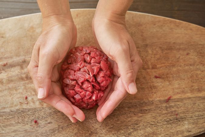 Crop woman forming steak tartar on cutting board
