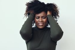 Black woman with her hands in her hair expressing frustration