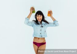 Happy and excited female with fresh juice glasses in hand on light background 4jEev5