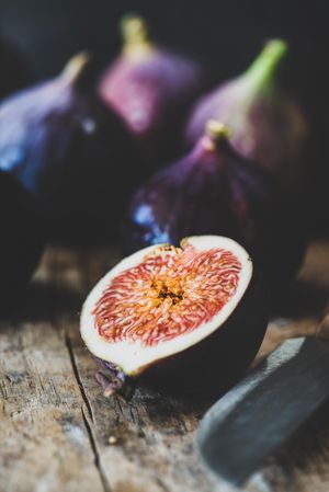 Figs, one halved, on wooden cutting board, close up, selective focud